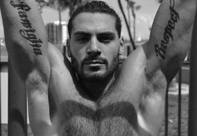 Close-up portrait of shirtless man doing chin-ups