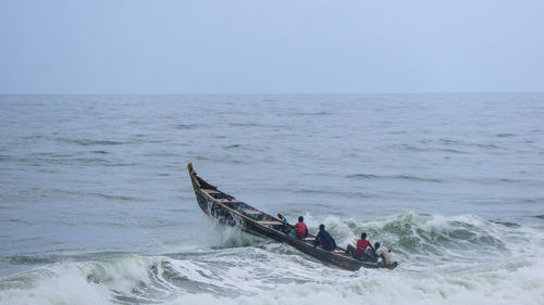 People on boat in sea against sky