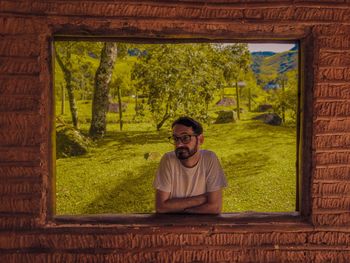 Portrait of young man standing by window