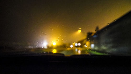 Illuminated road seen through wet glass