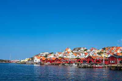 Sea by buildings against clear blue sky