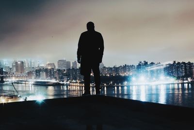 Rear view of silhouette of man with cityscape in background