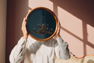 Man holding mirror while standing against wall