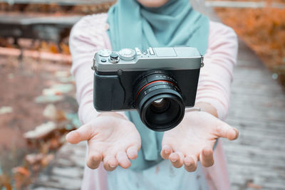 Midsection of woman holding digital camera