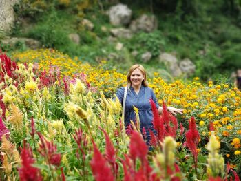 Portrait of a smiling young woman standing on yellow flowering plants