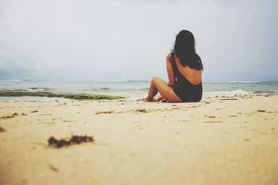 Rear view of woman sitting on beach