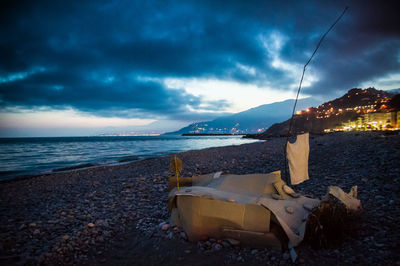 View of calm beach against cloudy sky