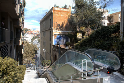 Road by buildings in city against sky