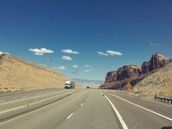 Road by mountains against sky