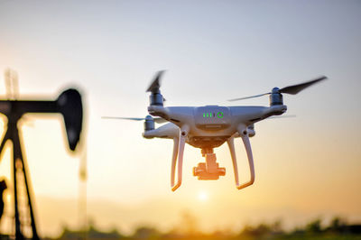 Drone flying against sky during sunset