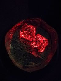 Close-up of illuminated red light against black background