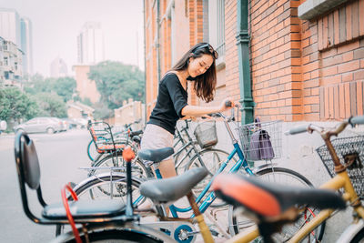 Woman with bicycle on street in city