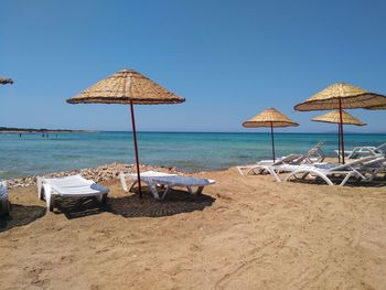 Deck chairs on beach against clear sky