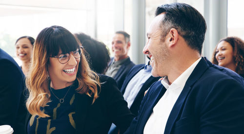 Male and female colleagues laughing in seminar