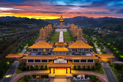 Temple by building against sky during sunset