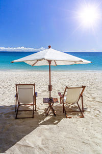 Deck chairs on beach against sky