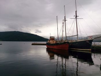 Sailboats moored on sea against sky