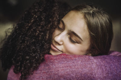 Girl embracing female friend with eyes closed