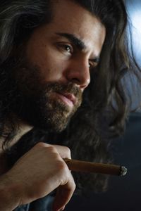 Man looking away while smoking cigar in darkroom