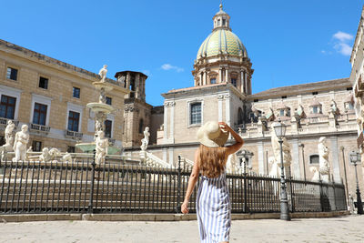 Rear view of woman looking at building against sky