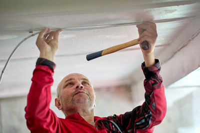 Low angle view of man with arms raised standing against sky