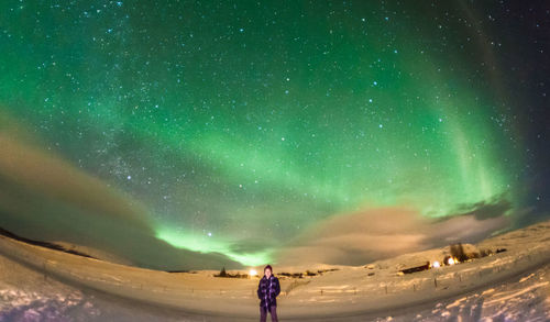 Rear view of man standing on land against sky at night