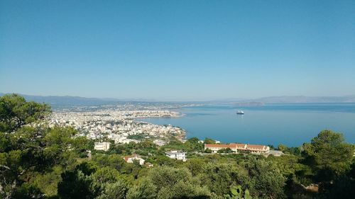 High angle view of cityscape by sea against clear sky