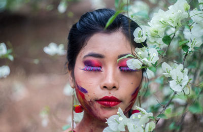 Young woman with eyes closes standing by flowering plant