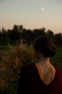 Rear view of woman on field against sky during sunset