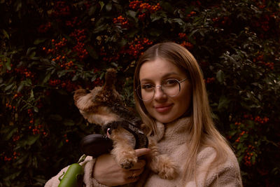 Young pregnant woman in glasses in the evening near a decorative tree with a yorkie dog.