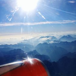 Aerial view of snowcapped mountains against bright sun