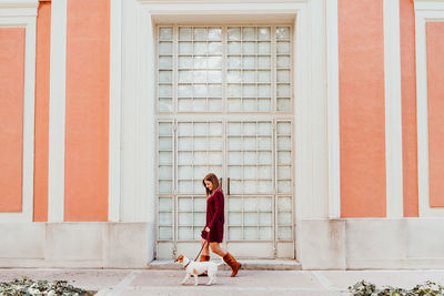 Woman walking with dog on footpath by entrance