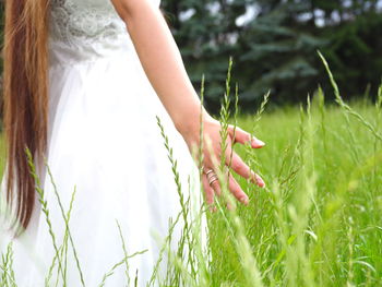 Close-up of woman hand on grass in field