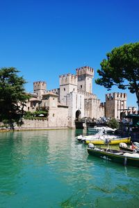 Canal amidst buildings against clear blue sky