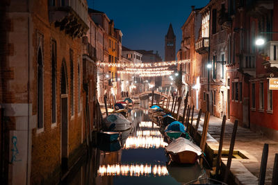 Canal amidst buildings in city at night