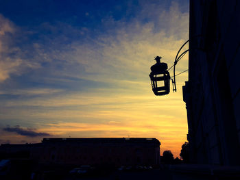 Low angle view of silhouette street amidst buildings against sky during sunset