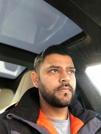 Low angle view of handsome mid adult man looking away while sitting in car