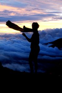 Silhouette boy standing against sky during sunset