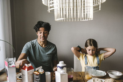 Father sitting with daughter while having breakfast at home