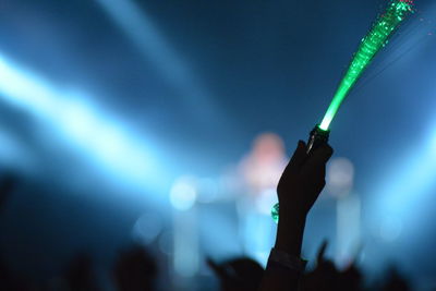 Close-up of hand holding illuminated lighting equipment at music concert 