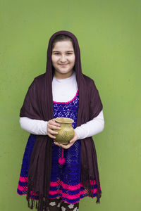 Portrait of smiling woman standing against wall