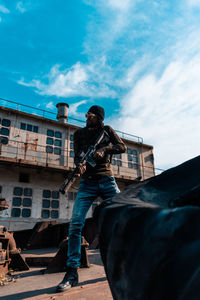 Low angle view of man holding camera against sky