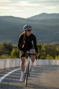 Smiling sportswoman cycling on costa blanca mountain pass in alicante, spain