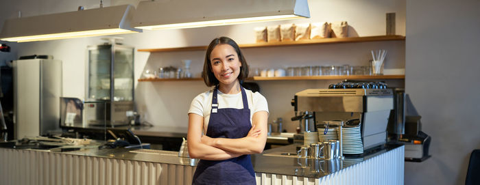 Portrait of young woman standing in kitchen