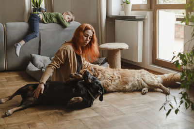 Ginger woman with three dogs cuddling on the floor pets friends at home with human. big dogs golden