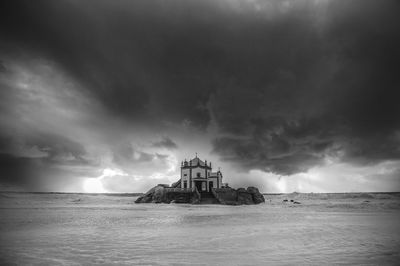 Church in middle of sea against storm clouds