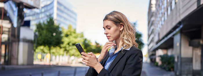 Female friends using mobile phone in city