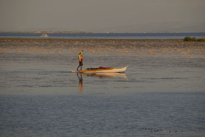 Man in boat on sea against sky