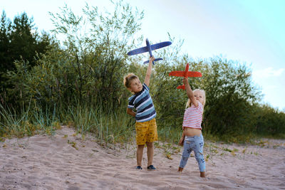 Boy and girl playing with airplanes on sand