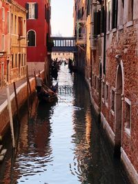 Man standing in gondola on canal against buildings